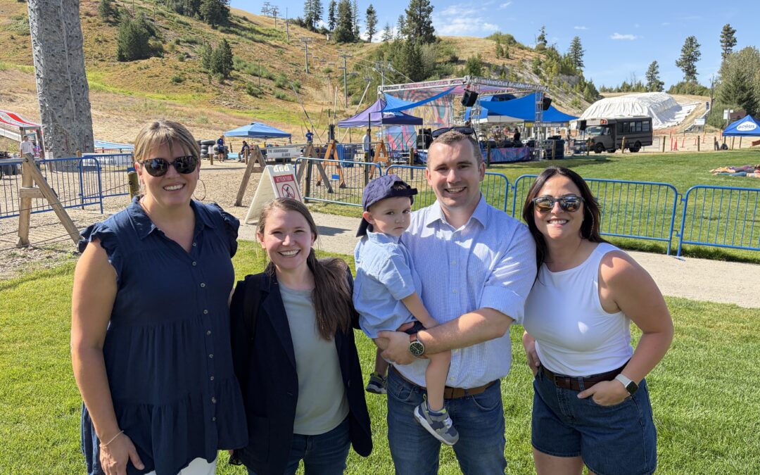 Welcome to Boise and Beyond team and clients at Bogus Basin's summer event area, with the concert stage and mountain behind them