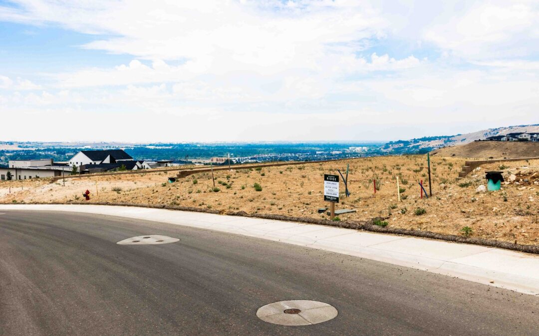 Graded new-construction building lots on a hillside in Harris Ranch, Southeast Boise, with a lot-for-sale sign and a view across the valley
