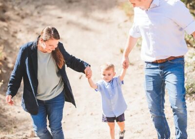 Parents walking hand in hand with their toddler up a dirt trail at Bogus Basin
