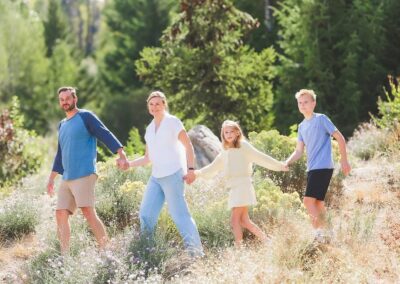 Family of four holding hands on a hillside trail at Bogus Basin during a client portrait session